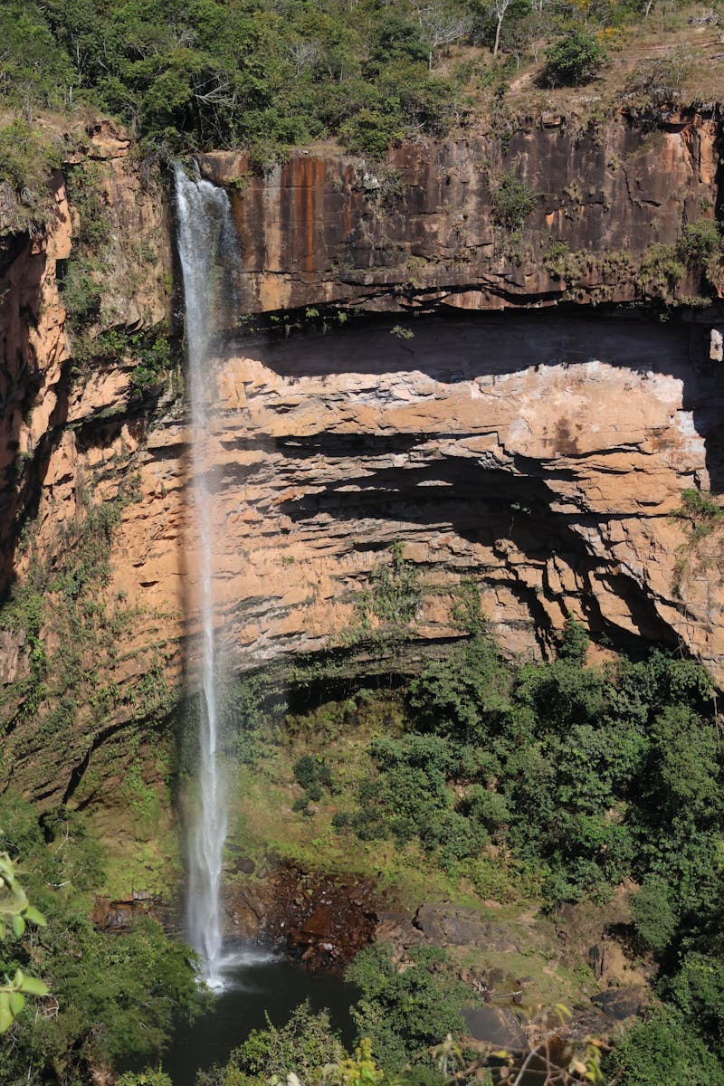 A waterfall is seen from above in the middle of a forest - Cachoeiras na Chapada dos Veadeiros