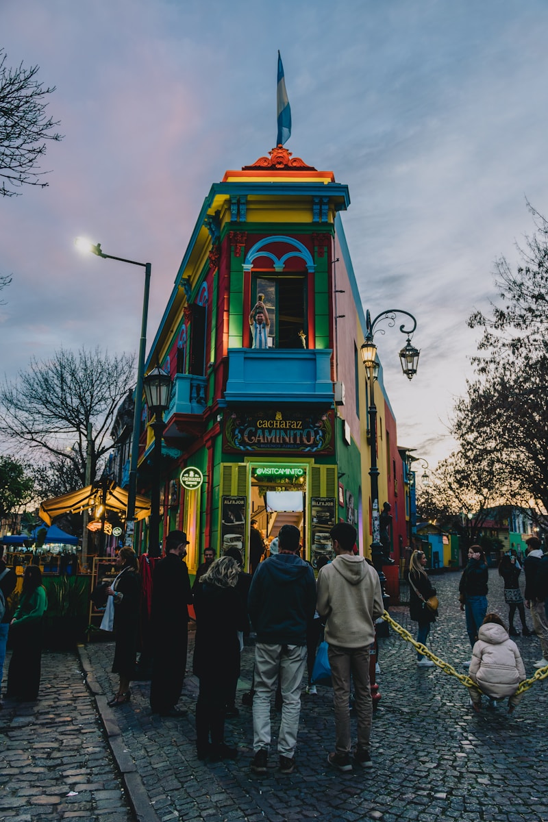 a group of people standing outside of a colorful building - Museus Imperdíveis em Buenos Aires