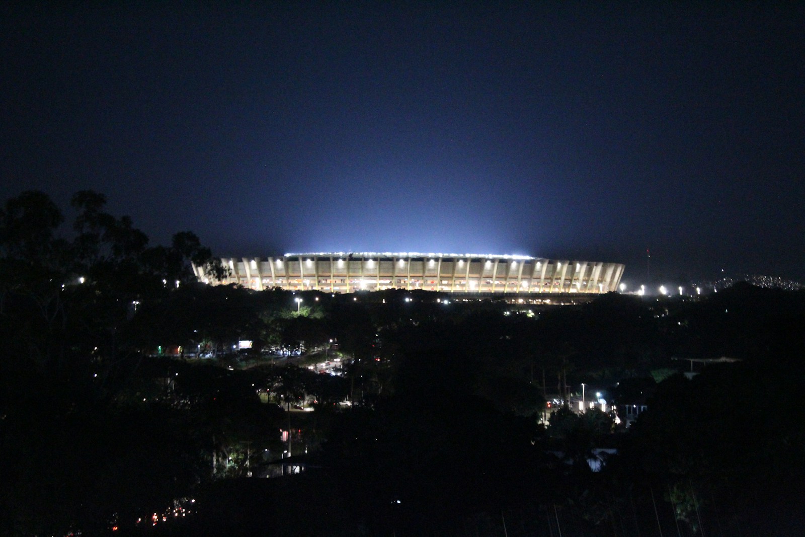 a stadium lit up at night with lights on - Gastronomia Mineira