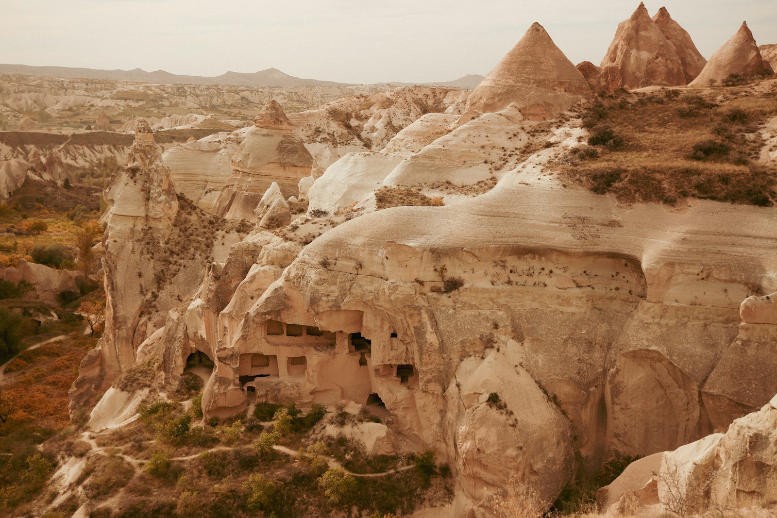 a group of rock formations in the desert - Passeios de Balão Capadócia