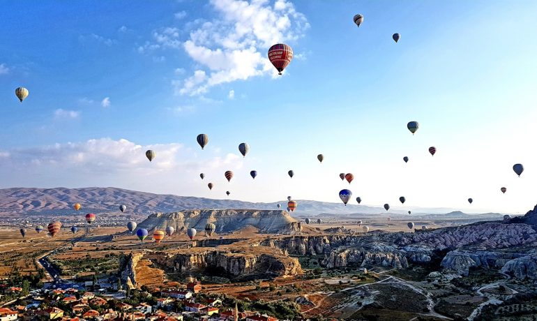 hot air balloons flying over the mountains during daytime - Passeios de Balão Capadócia