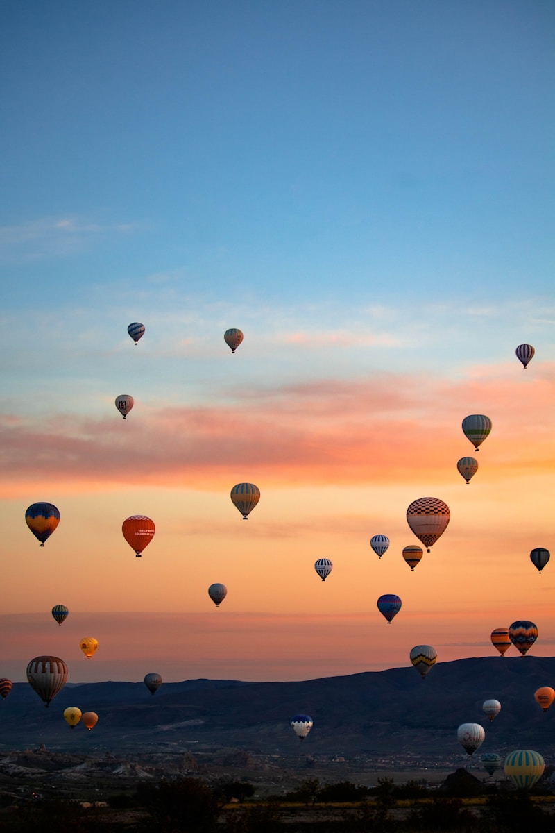 a group of hot air balloons flying in the sky - Passeios de Balão Capadócia